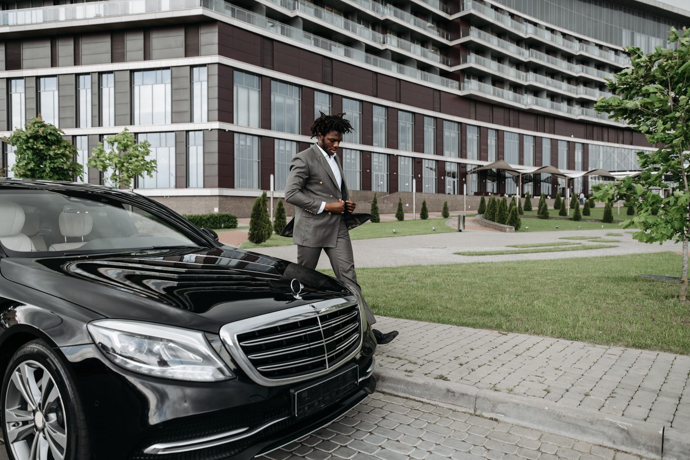 Executive Mercedes-Benz with chauffeur outside a modern building
