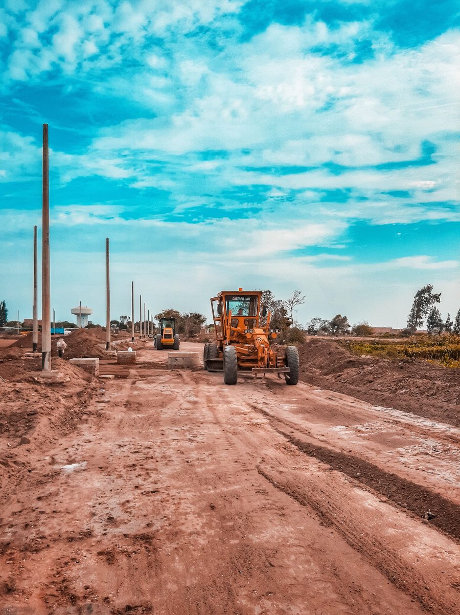 Grader working on a road under a wide sky
